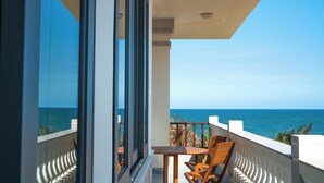 A balcony with a view of the ocean, wooden chairs, and a table. - Blooming Lotus Resort (Tien Thanh)