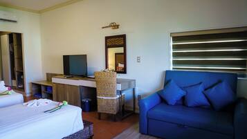 Una habitación de hotel con una cama, un escritorio con computadora, un sofá azul y un espejo.