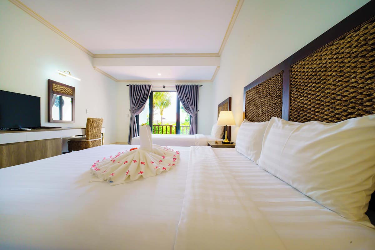 A hotel room with a bed, a desk, a chair, a television, and a view of the outdoors.