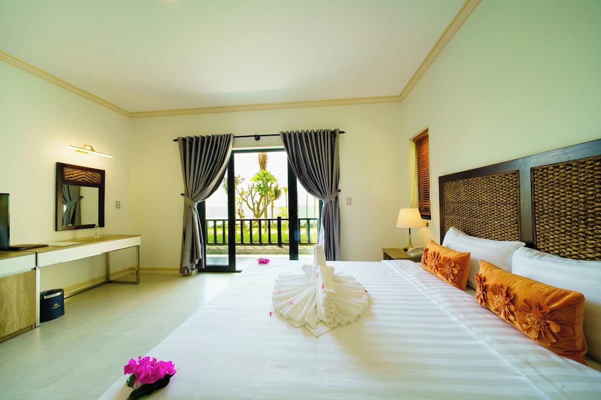 A hotel room with a bed, a desk, a mirror, and a view of the outdoors.