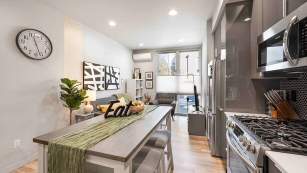A modern kitchen with a dining area, stainless steel appliances, and a large window providing natural light. - Newly Modern 2B2B Home near Seatac - Golf course (Seattle)