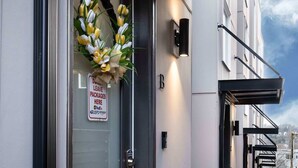 A modern building entrance with a glass door, a wreath, and a sign indicating packages are left here. - Newly Modern 2B2B Home near Seatac - Golf course (Seattle)