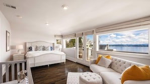 A bedroom with a large window, a bed, a sofa, and a crib.