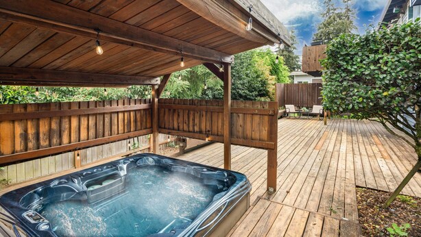 Eine Holzterrasse mit Whirlpool, einer Holzpergola und einem Holzzaun.