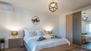 A modern bedroom with a large bed, bedside lamps, a wardrobe, and a mirror.