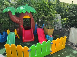 A children's play area with a slide, climbing structure, and a fenced play zone.