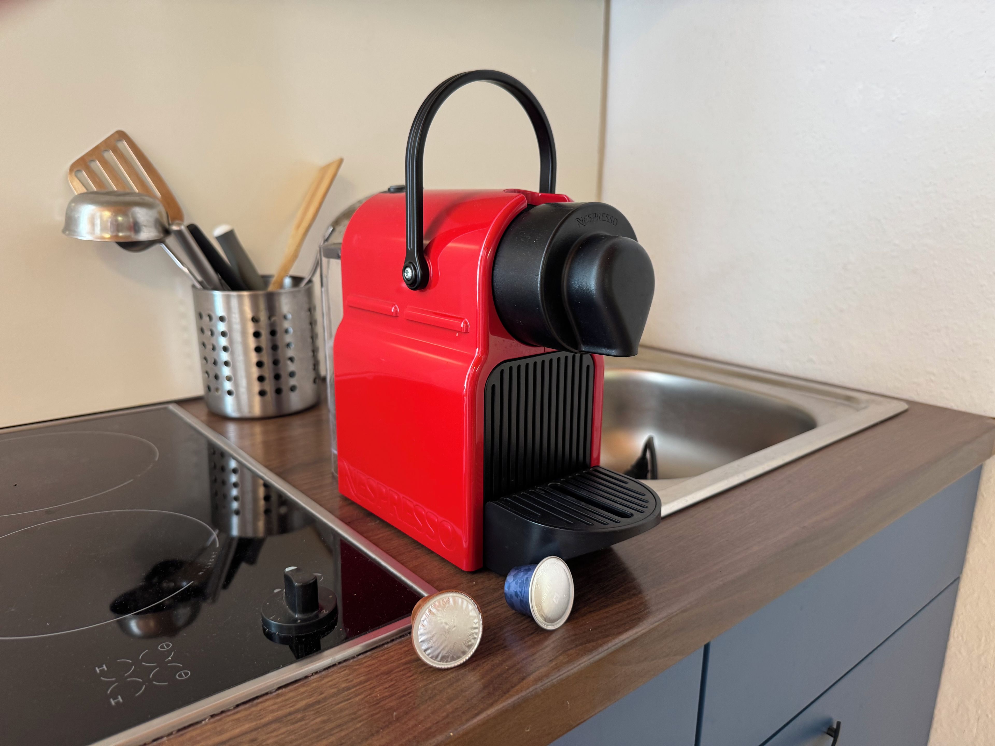 Ein roter, tragbarer Espressokocher auf einer Küchenarbeitsplatte mit einer Edelstahl-Spüle.
