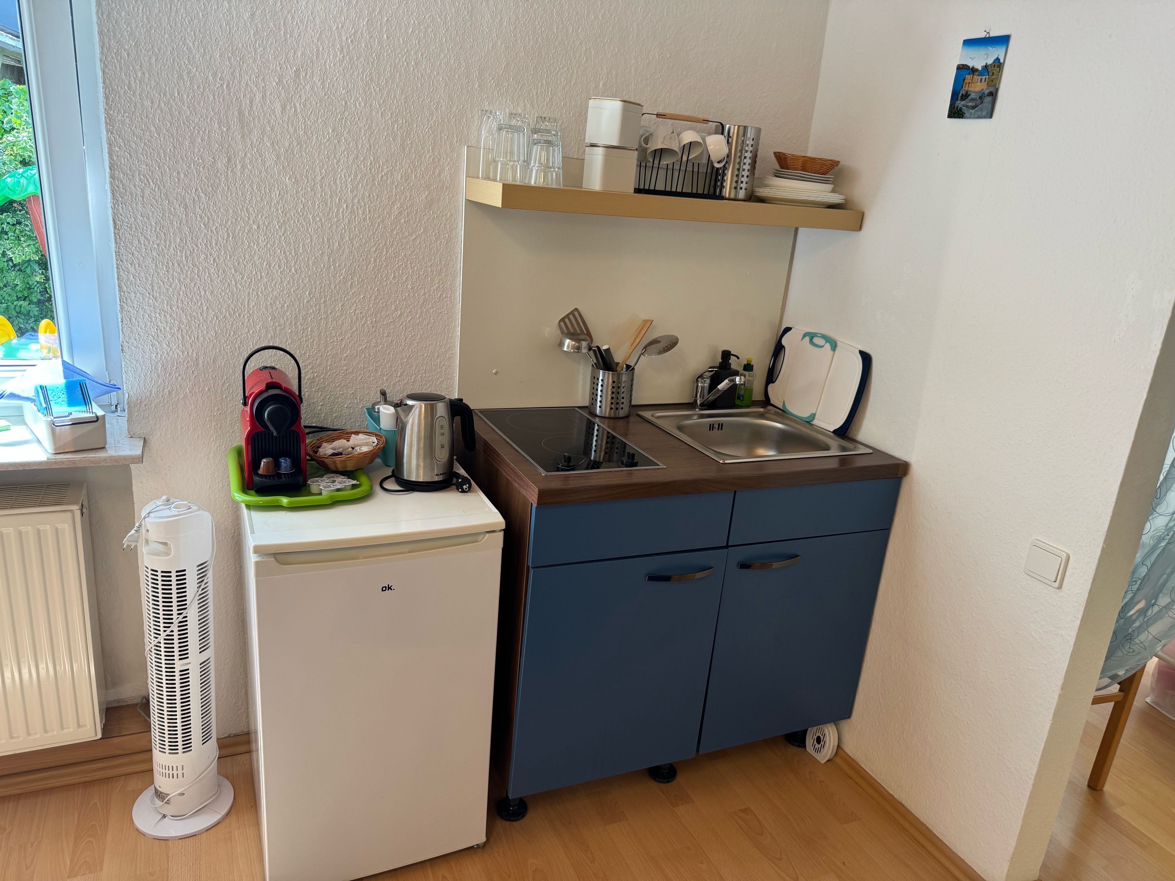 A compact kitchenette with a built-in stove, a sink, and a small refrigerator.