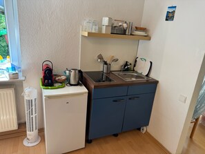 A compact kitchenette with a built-in stove, a sink, and a small refrigerator.