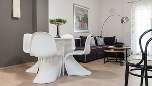 Ein modernes Wohnzimmer mit einer Couch, einem Esstisch mit Stühlen, einer Stehlampe und einem Bild an der Wand.