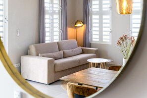 A living room with a sofa, a round table, and a lamp.