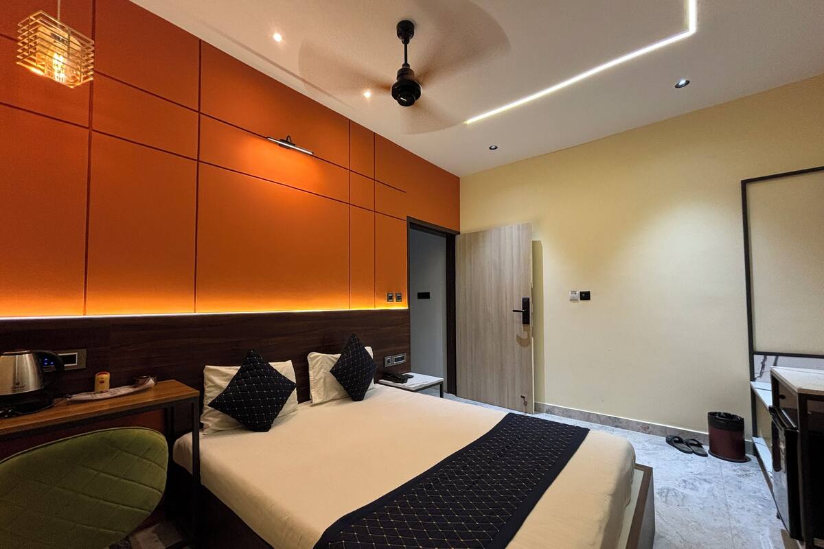 Habitació d'hotel amb un llit gran, una taula de treball amb cadira, un armari i un bany amb dutxa i vàter.