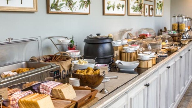 A buffet setup with various food items and a large black pot, likely for cooking. - Hotel Ambassador  (Varanasi)