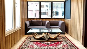 A modern living room with a glass coffee table, a brown sofa, and a patterned rug. - Hotel Ambassador  (Varanasi)