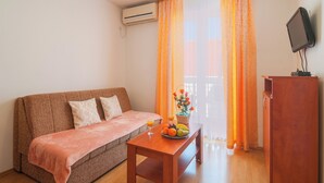Una sala de estar acogedora con un sofá, una mesa de madera con frutas y bebidas, un televisor y un mueble de madera.