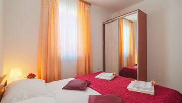 A hotel room with a bed, a mirror, and curtains.
