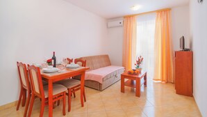 Un comedor con una mesa y sillas de madera, un sofá y una mesita auxiliar con fruta.