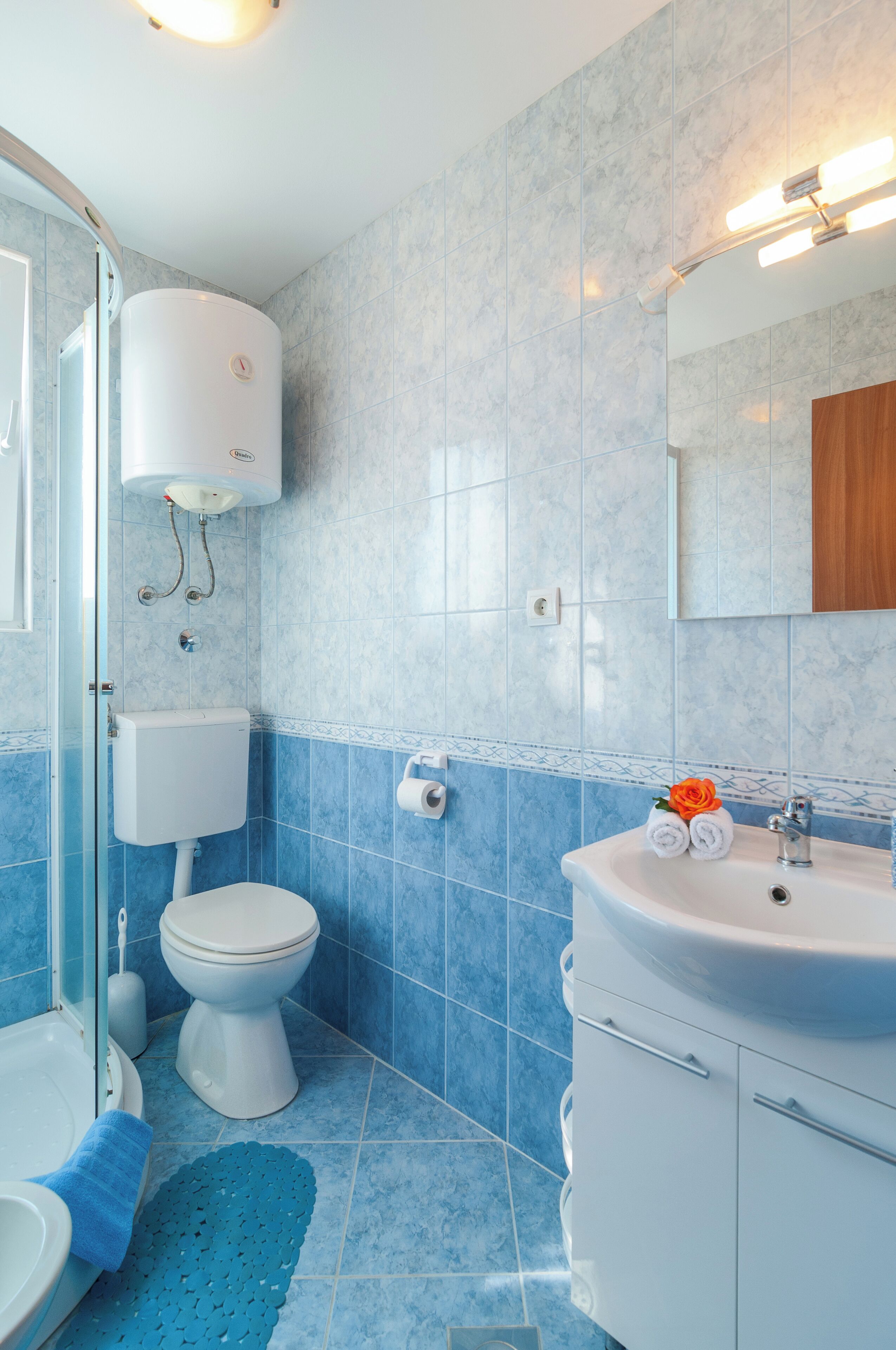A bathroom with a toilet, sink, and shower area.