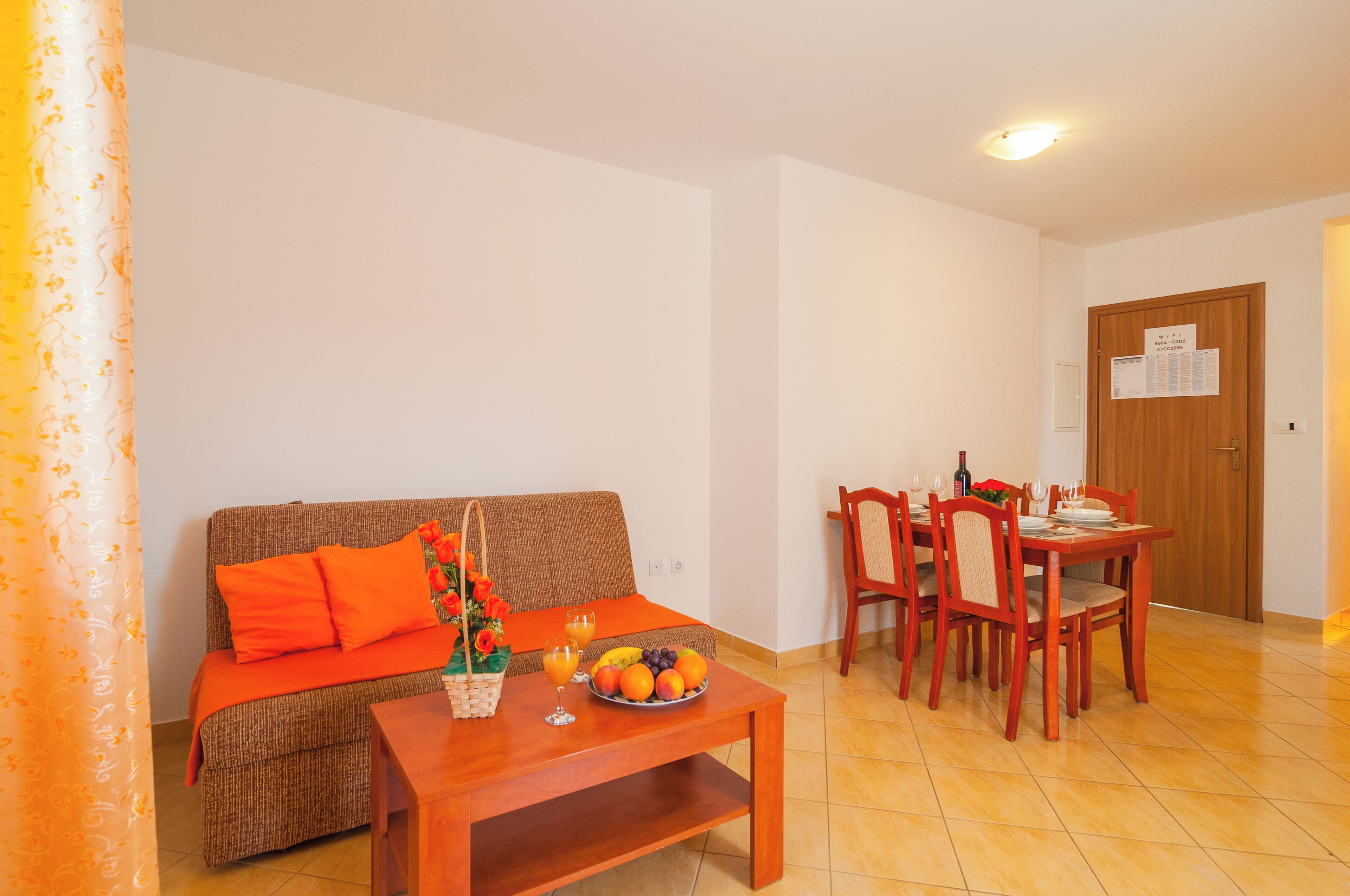 A living room with a sofa, coffee table, and dining table set with fruit and glasses.