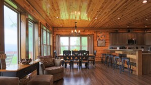 A spacious wooden cabin interior with a dining area, kitchen, and seating. - Private Getaway w/ Theater & Views Near Dollywood! (Sevierville)