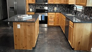 Une cuisine moderne dotée de meubles en bois, d’un réfrigérateur en acier inoxydable, d’un four à micro-ondes, d’un four traditionnel et d’un lave-vaisselle.