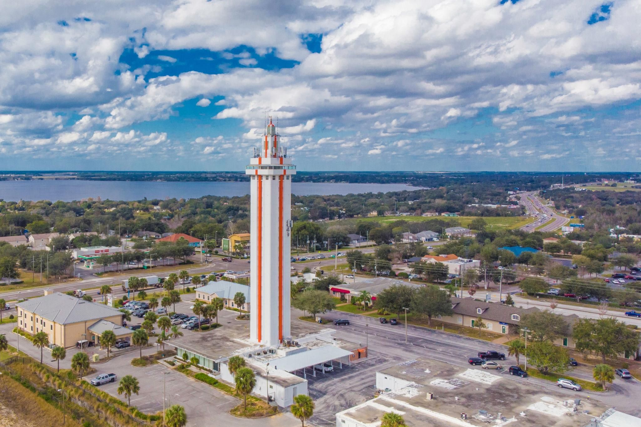 Une ville côtière qui se distingue par une tour blanche et orange imposante, un port de plaisance et un mélange de bâtiments résidentiels et commerciaux.