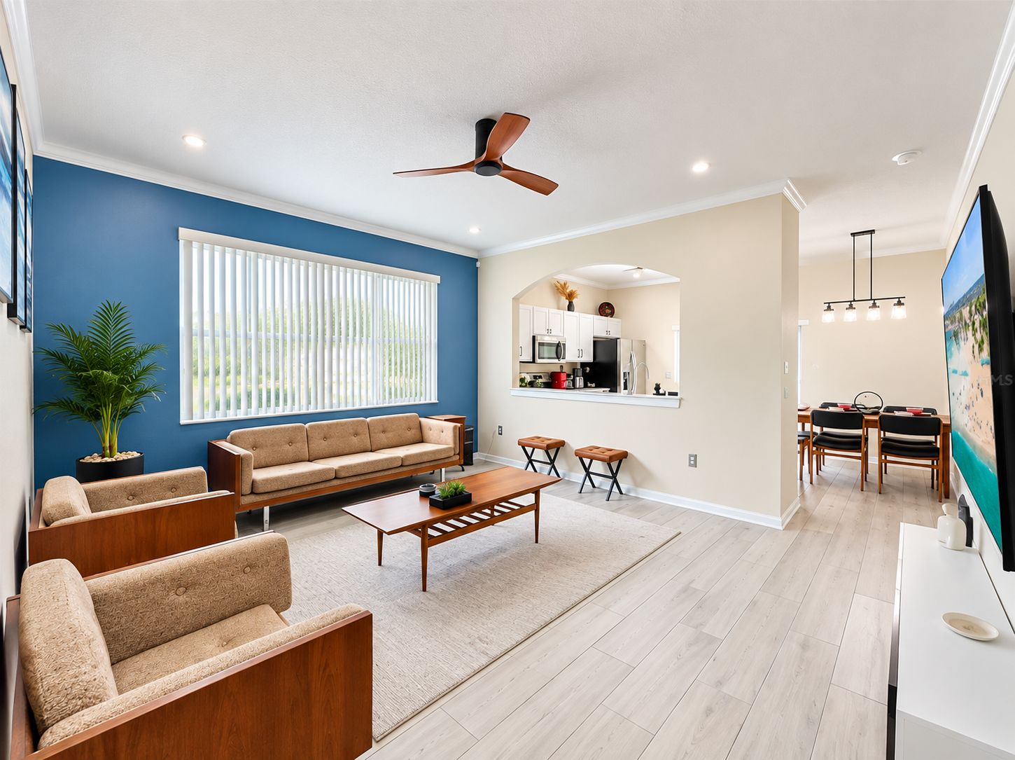A modern living room with a sofa, coffee table, and a dining area with chairs and a TV.