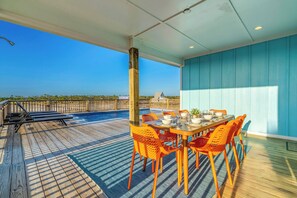 Um terraço com mesa e cadeiras, com vista para uma piscina e um edifício ao longe.