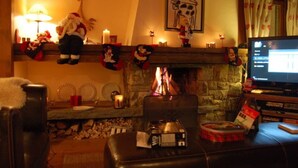 Ein gemütliches Wohnzimmer mit Kamin, Fernseher und festlicher Dekoration.