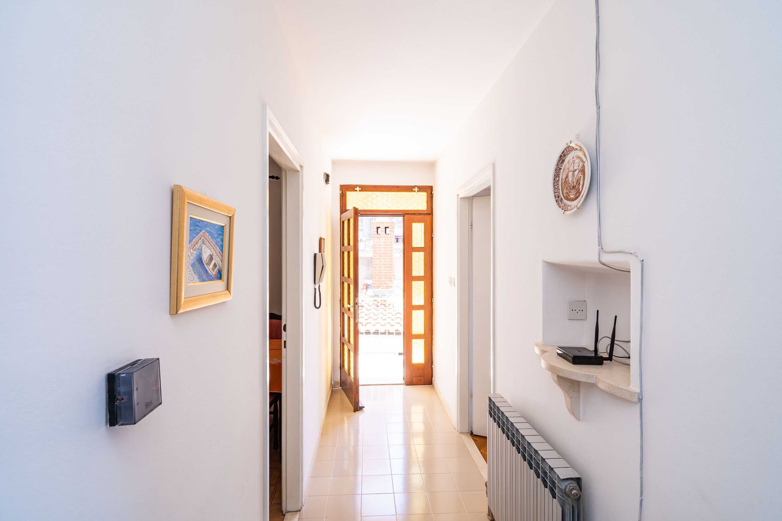 A hallway with a radiator, a framed picture, and a shelf with electronic devices.