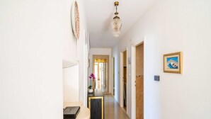 A hallway with a desk, a vase with flowers, and a framed picture on the wall. - Apartments Stella (Dubrovnik)