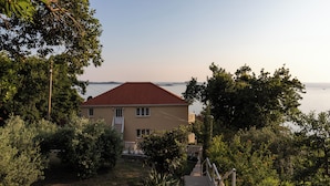 A house with a red roof, surrounded by greenery and a view of the sea. - Apartments Belenum (Zupa dubrovacka)