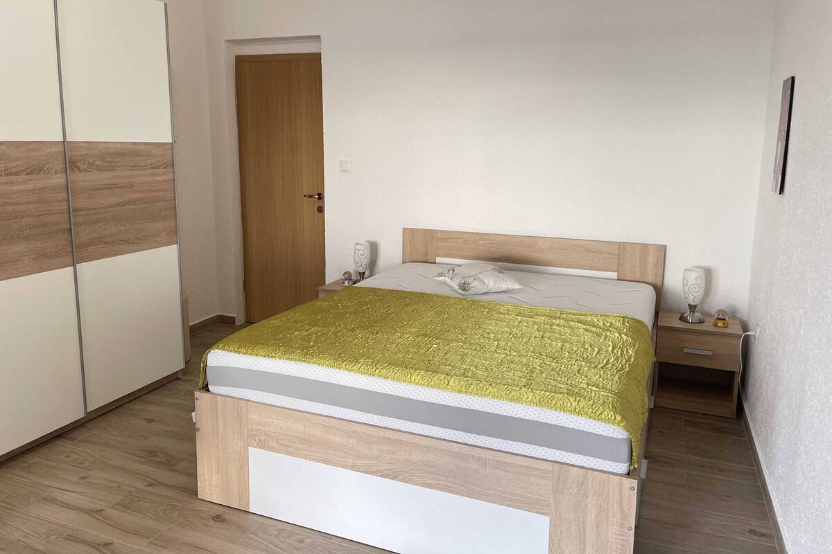 A bedroom with a bed, bedside tables, a wardrobe, and a door.