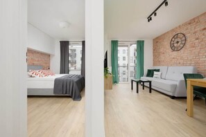 Un apartamento moderno con una cama, un sofá, una mesa de comedor y una pared de ladrillo.
