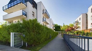 Un edificio residencial moderno con balcones, un camino pavimentado y una cerca de metal.