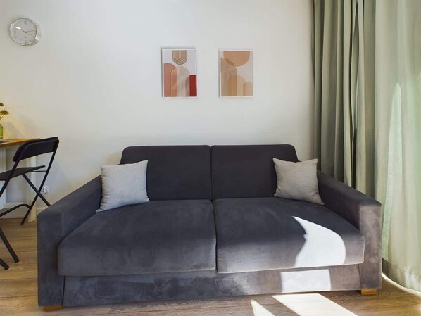 Una sala de estar moderna con un sofá gris oscuro, dos cojines y arte abstracto en la pared.
