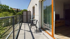 Un balcón moderno con puerta de vidrio, una mesita y dos sillas.