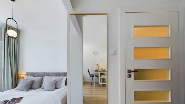 Una habitación de hotel con cama, escritorio y puerta de varios paneles.