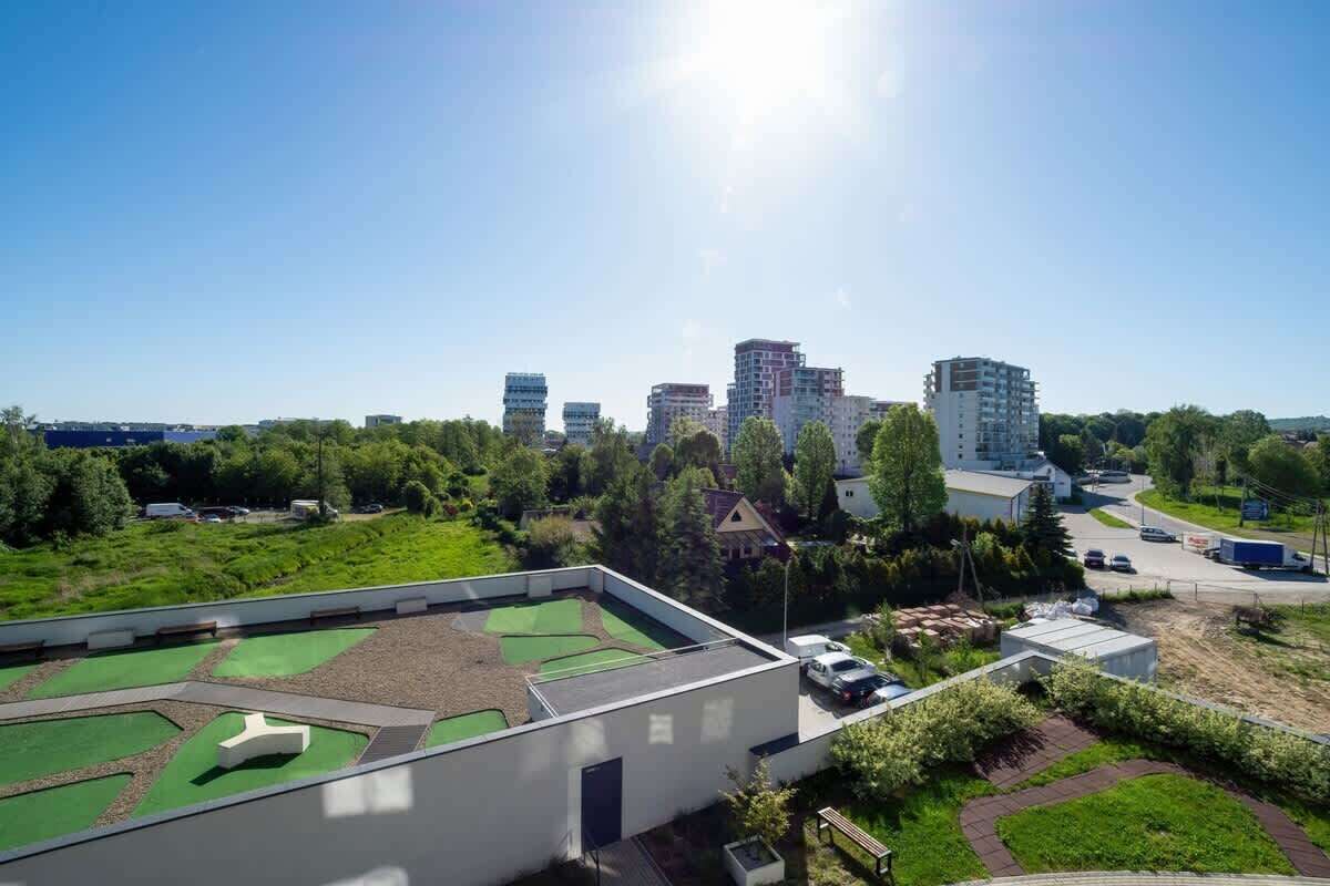 Een dak met een groen sportveld en een parkeerplaats.