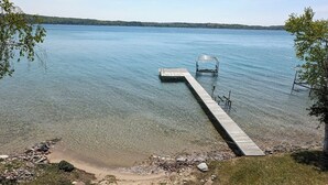 Un lago tranquilo con un muelle de madera que se adentra en el agua, rodeado de zonas verdes y árboles.