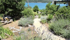 A garden path leading to a body of water with mountains in the background. - Apartments More & Ja (Ston)