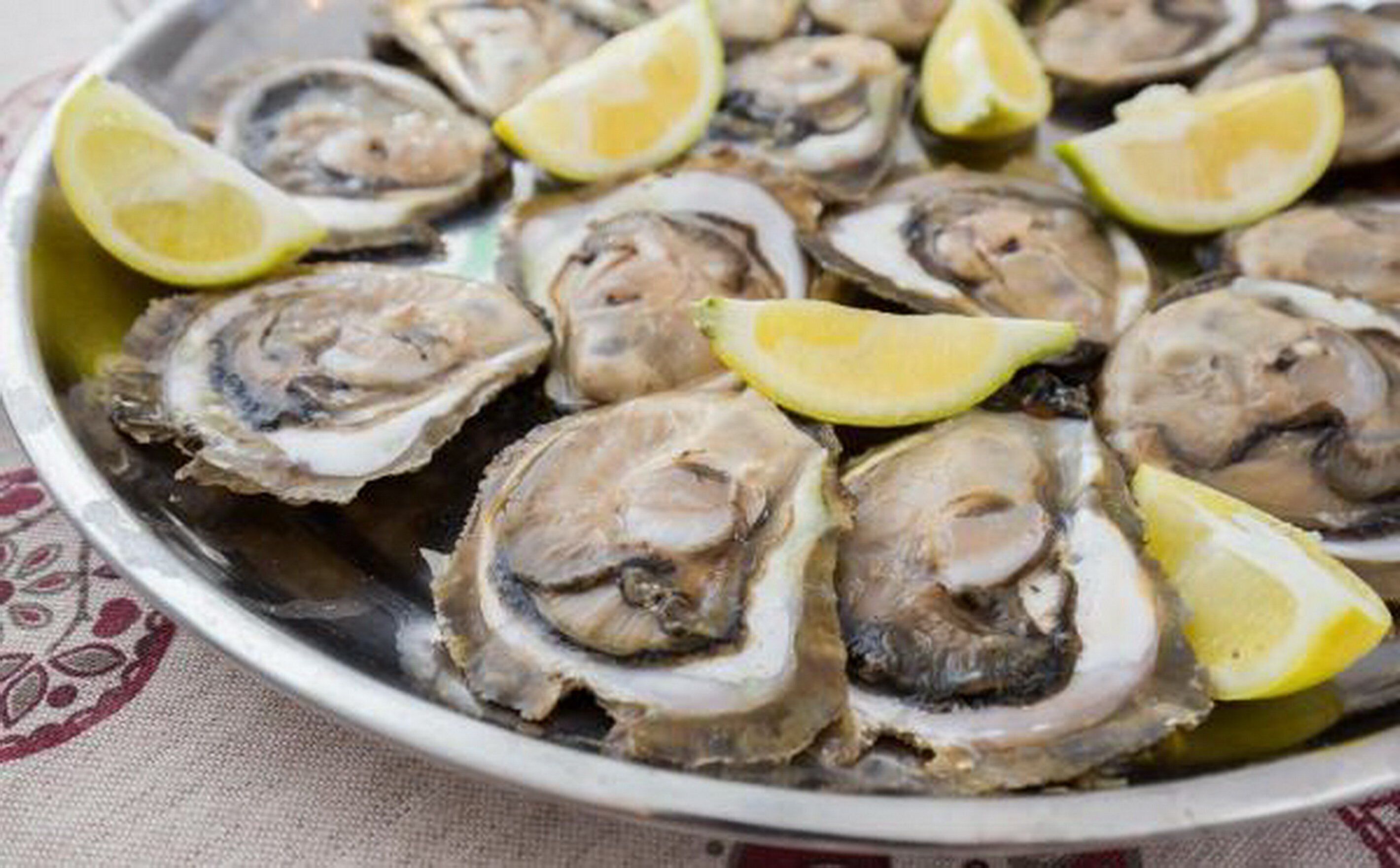 Un plato de ostras con gajos de limón.