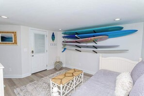 A bedroom with a bed, a bench, and a wall-mounted surfboard rack.