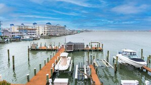 Un port de plaisance avec des bateaux amarrés, une jetée en bois et un hôtel doté de nombreux balcons.