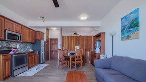 Een moderne keuken met houten kastjes, een eethoek met een tafel en stoelen, en een woonkamer met een bank.