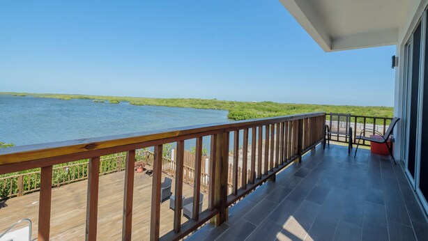 Een balkon met uitzicht op water en groen.