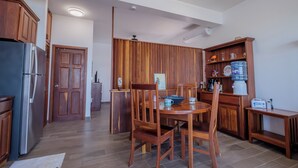Een keuken met houten kastjes, een koelkast, een eettafel met stoelen en een waterdispenser.