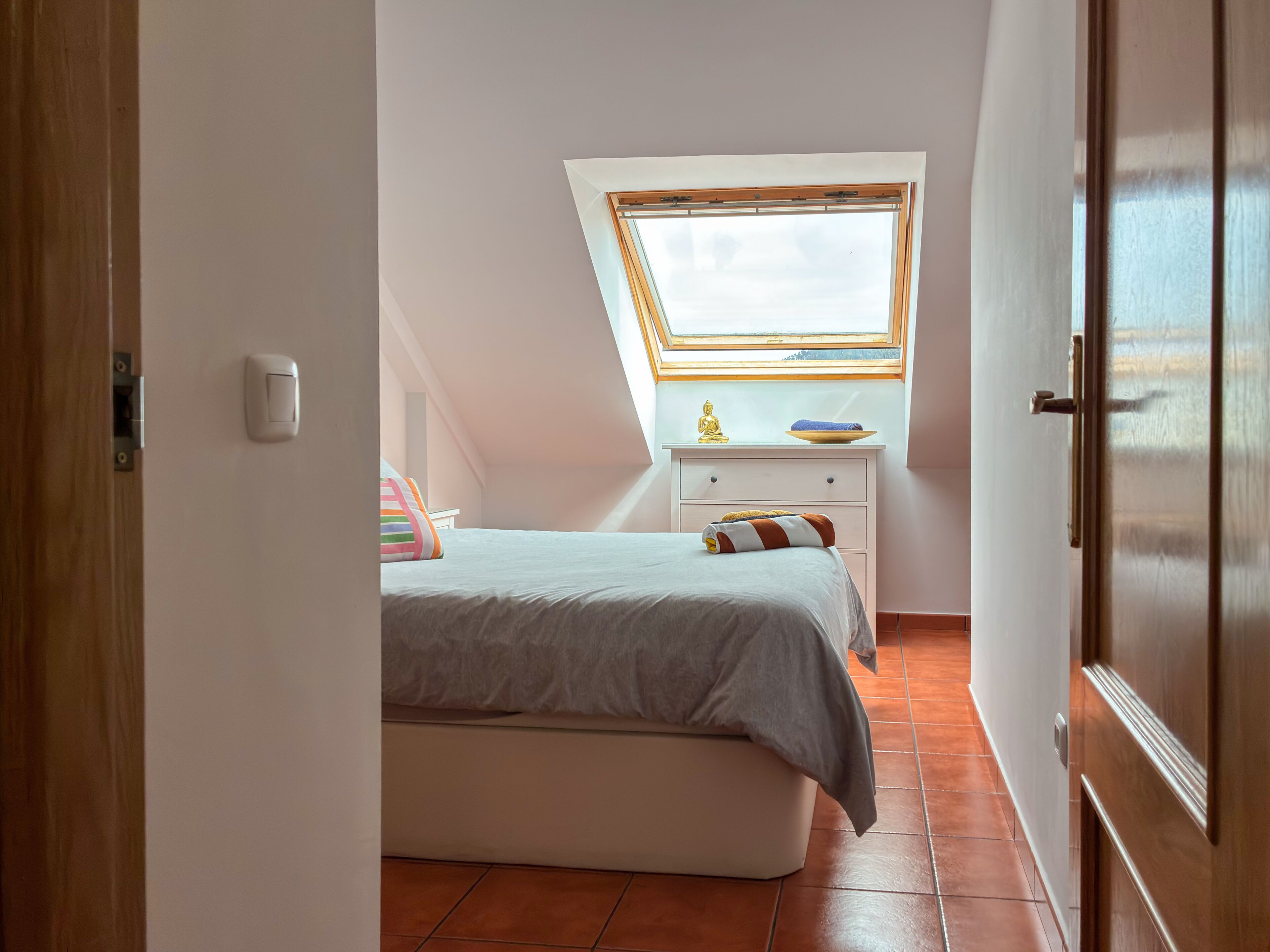 Ein Schlafzimmer mit Bett, Nachttisch, Fenster und Tür.