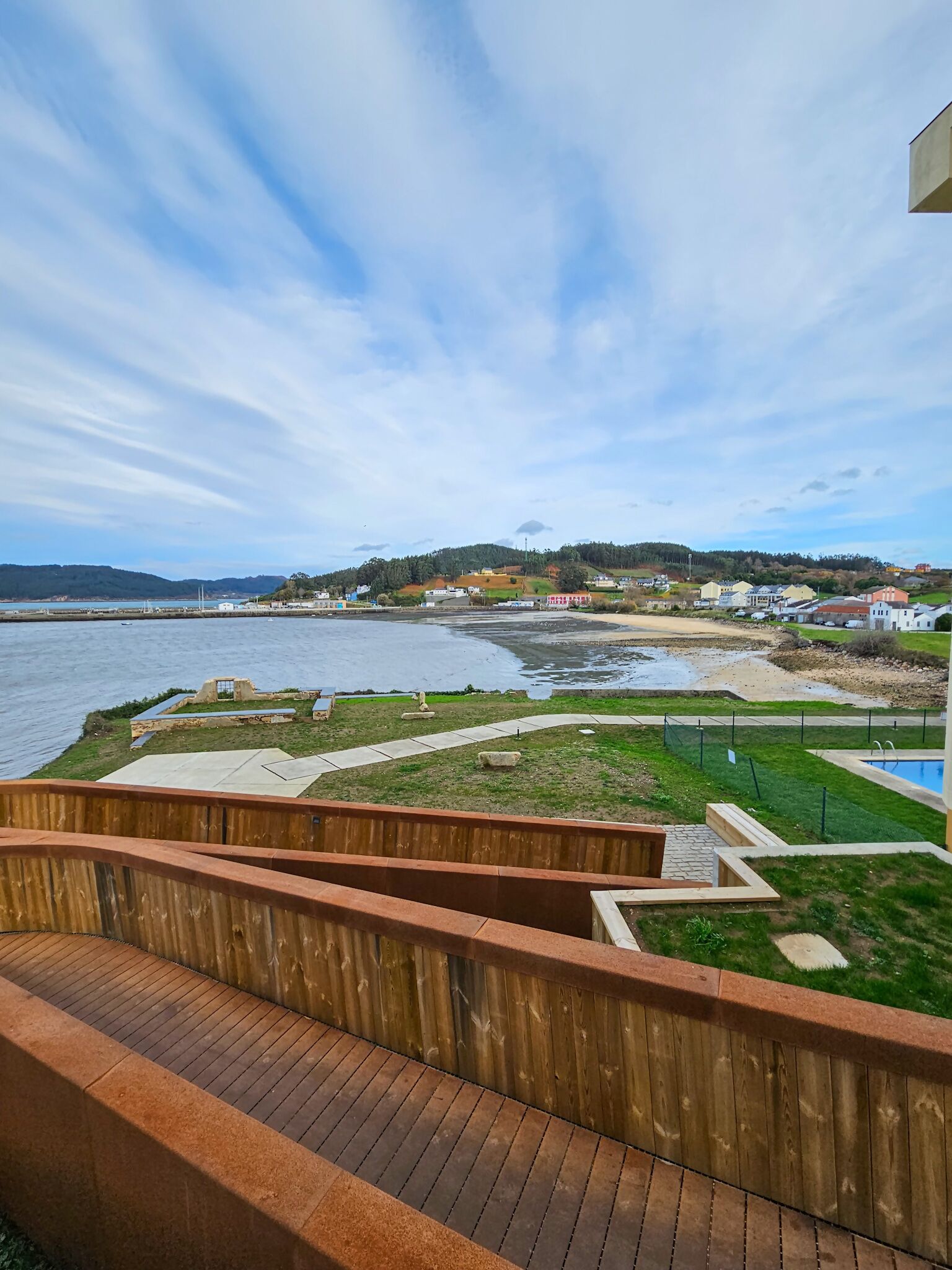 A waterfront property with a wooden deck and a swimming pool.