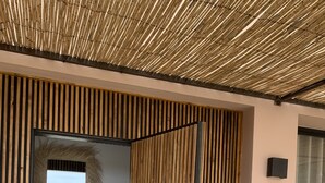 A modern interior with a wooden slatted wall, a black door, and a small table with decorative items. - Dar Almajula (Essaouira)